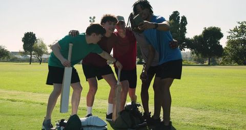 Youth cricket team taking selfie on grass field showing camaraderie and practice gear