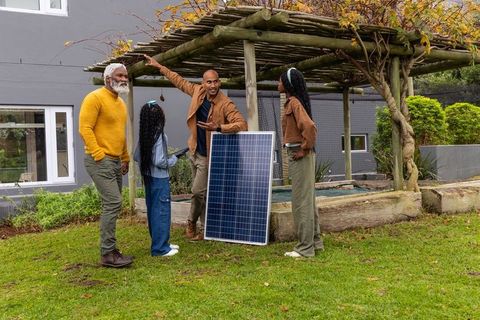 Multigenerational african american family discussing solar panel at backyard pergola
