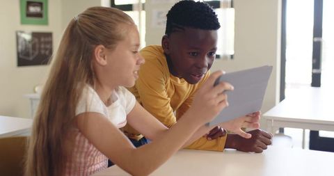 Multicultural children collaborating on tablet in bright classroom digital learning and engagement