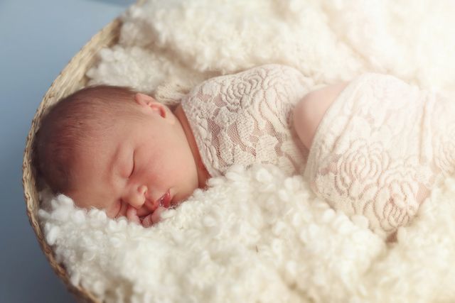 Newborn baby sleeping peacefully in soft blanket and lace wrap, laying in a basket. Perfect for illustrating the serenity and innocence of newborn life. Ideal for family-oriented projects, parenting blogs, baby product advertisements, and maternity care promotions.