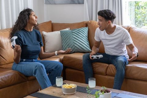African couple playing video games on sofa, playful competition in cozy living room