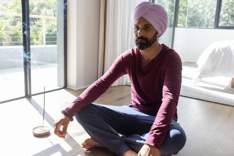 Indian Man Meditating with Incense in Sunlit Bedroom