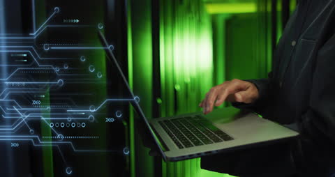 IT Technician Using Laptop in Energetic Server Room Environment