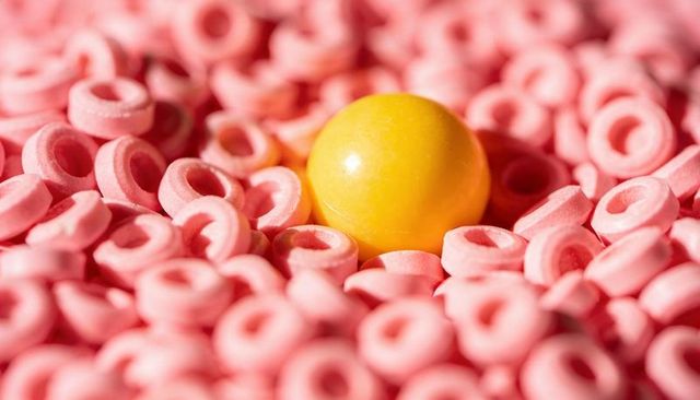 Glossy yellow candy nestled in pink ring sweets macro closeup with shiny glint