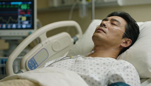 Middle-aged man lying in hospital bed wearing nasal cannula and cardiac monitoring leads