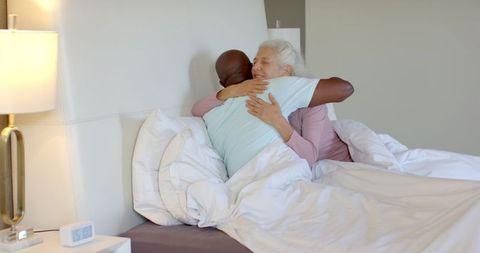 Diverse Senior Couple Embracing Tenderly in Modern Bedroom