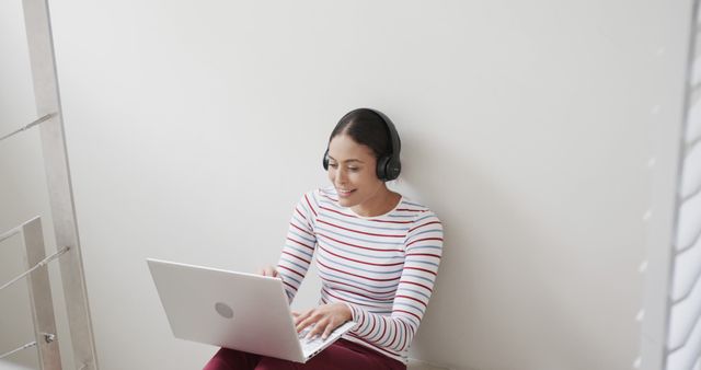 Woman Wearing Headphones Working on Laptop in Modern Home - Download Free Stock Images Pikwizard.com