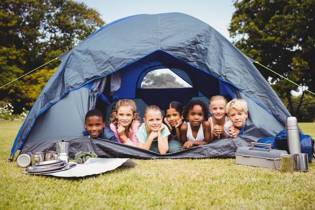  Smiling children lying in the tent together in the park