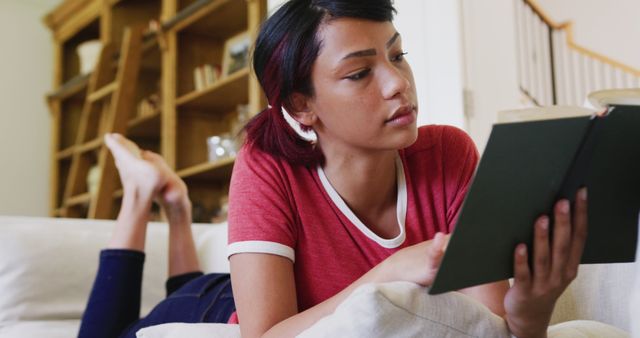 Young Woman Reading Book Comfortably on Couch - Download Free Stock Images Pikwizard.com