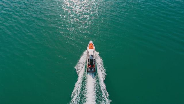 Aerial speedboat cutting turquoise water leaving twin white wakes and foam trail