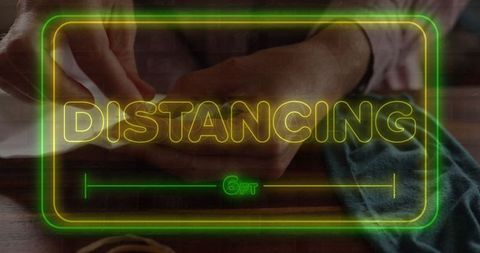 Neon social distancing sign over mask crafting scene