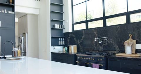 Modern Black White Kitchen Showcasing Quartz Island, Matte Range, Dark Marble Backsplash