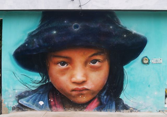 Colorful mural on outdoor blue wall features close-up of young girl with intense gaze, showcases exquisite detail and artistic skill. Excellent for articles on street art, urban cultures, or child-focused initiatives. Suitable for decorating blogs, galleries, or cultural heritage content.