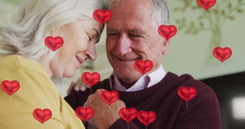 Senior couple surrounded by romantic heart icons