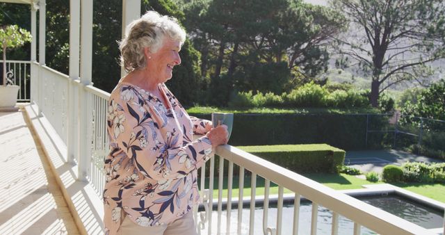 Caucasian senior woman holding coffee cup smiling while standing in the balcony at home. retirement senior lifestyle living concept