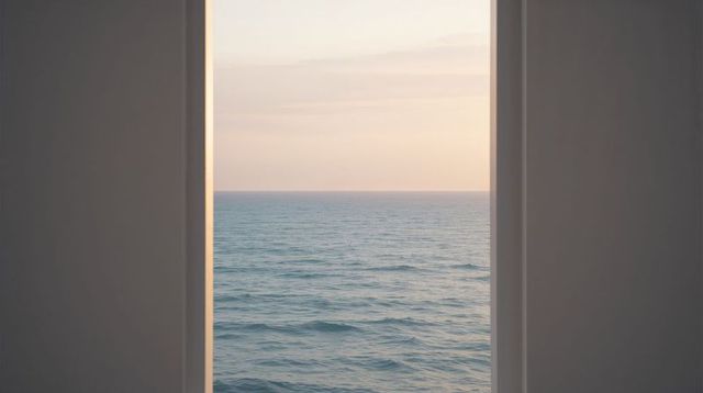 Minimalist framed view revealing rippling sea at dawn with pastel sky and warm light