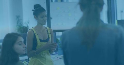 Woman in Yellow Overalls Leading Creative Brainstorming Session in Modern Open Office