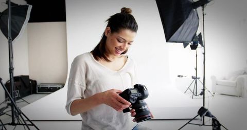 Female Photographer Adjusting Camera Settings in Minimalist Studio