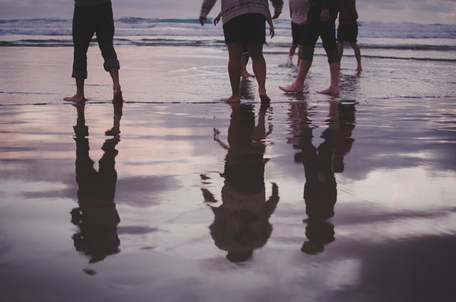 Group Walking Along Beach at Sunset with Reflection on Wet Sand - Download Free Stock Photos Pikwizard.com
