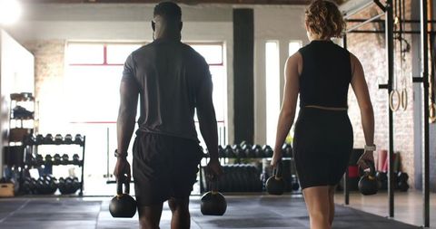 Diverse Workout Partners Carrying Kettlebells in Urban Gym
