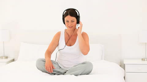 Pregnant Woman Relaxing with Music in Serene Bedroom