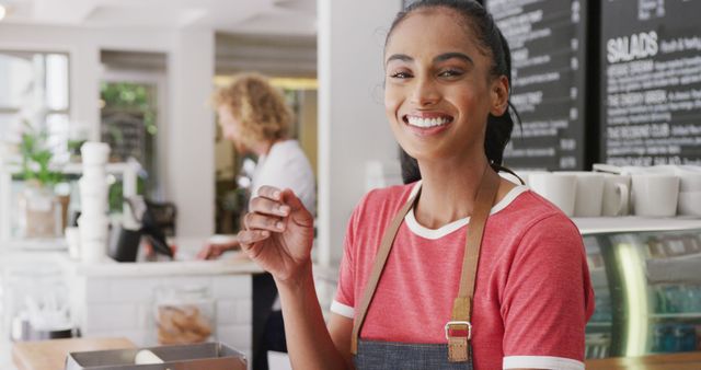 Portrait of happy biracial female barista, smiling behind the counter in cafe. Local business owner and hospitality concept.