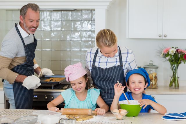 Happy parents and kids preparing food in kitchen at home