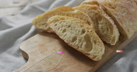 Sliced rustic artisan bread resting on wooden board with light linen and open crumb