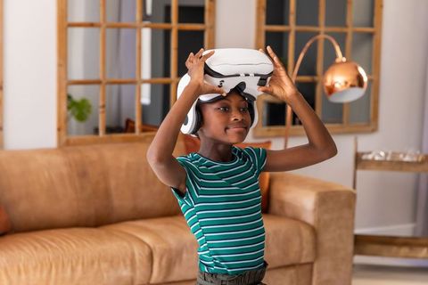 African american teen trying virtual reality headset in cozy modern living room