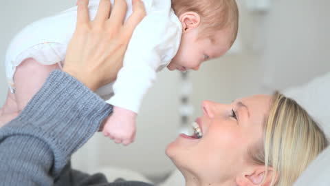 Mother Joyfully Holding Baby While Smiling
