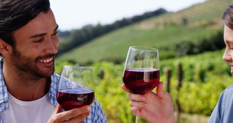 Young Adults Wine Tasting in Scenic Vineyard Landscape