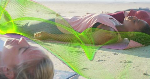 Women lying and relaxing on beach yoga mats with neon wave overlay for wellness