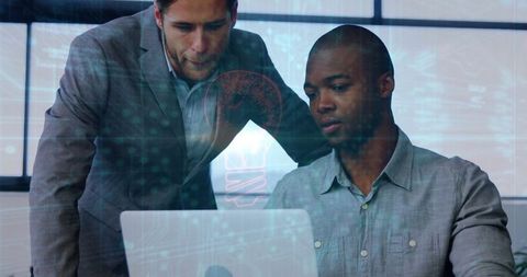 Two businessmen analyzing data on laptop in modern office