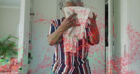 Senior woman holding towel to face during morning skincare routine in serene dressing area