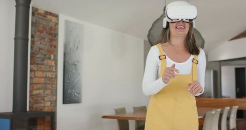 Mature woman wearing vr headset exploring virtual reality in modern open home dining room