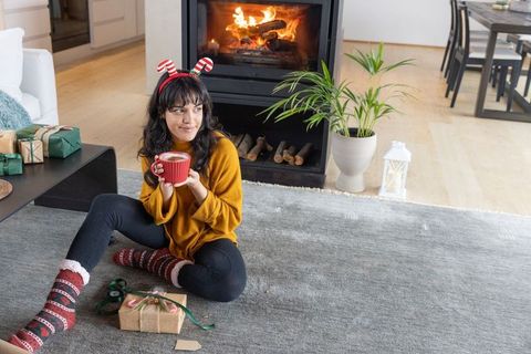 Woman enjoying christmas wrapping by cozy fireplace