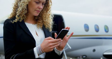 Successful Businesswoman Using Phone Beside Private Jet on Tarmac