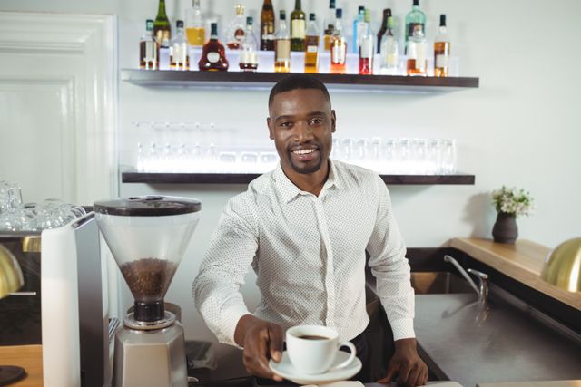 Waiter offering a cup of coffee at a restaurant counter, smiling warmly. Ideal for use in hospitality industry promotions, coffee shop advertisements, customer service training materials, and restaurant marketing campaigns.
