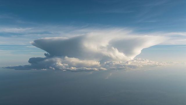 Towering anvil cumulonimbus cloud spreading over horizon from aerial viewpoint, high altitude