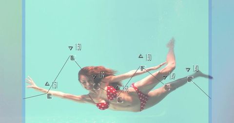 Swimmer gliding underwater in red polka dot bikini with data overlay and turquoise pool