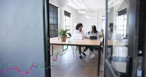 Startup team collaborating in modern open-plan office with laptops, tablet and natural daylight