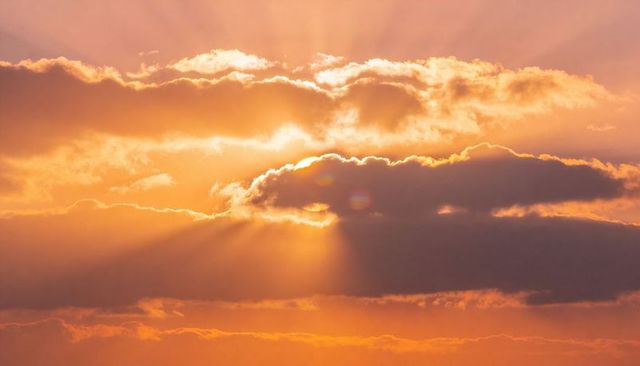 Golden Sunrise Breaking Through Cloud Layers with Crepuscular Rays and Lens Flare