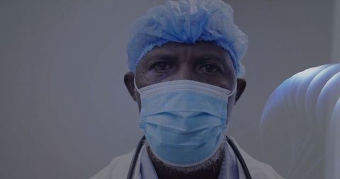 Senior doctor with surgical cap and mask standing in clinic