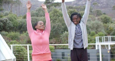 African american couple stretching together on balcony during outdoor morning workout