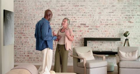 Couple standing and conversing in minimalist living room with exposed brick wall and neutral decor