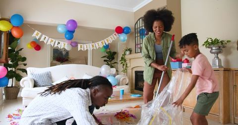 Family tidying up after birthday celebration at home