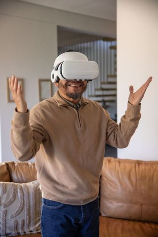 Man enjoying virtual reality at home wearing white vr headset on cozy leather couch