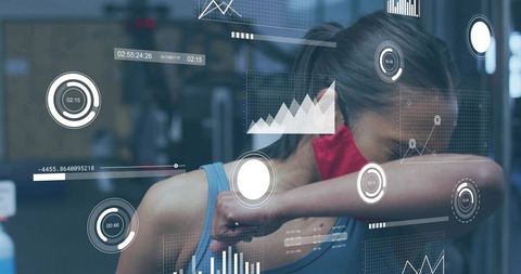 Female athlete wearing red mask wiping face with forearm in gym with futuristic HUD