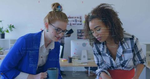 Two businesswomen collaborating reviewing code in office