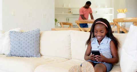 Father Observing Daughter Using Smartphone in Modern Living Room